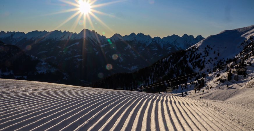Pista appena battuta a Obereggen, con il sole sopra le creste delle Dolomiti.