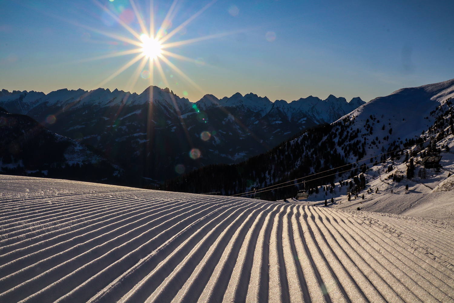 Pista appena battuta a Obereggen, con il sole sopra le creste delle Dolomiti.
