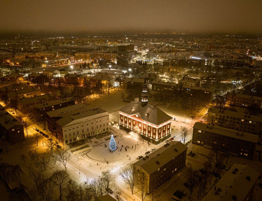 Veduta dall’alto del Municipio di Narva e della piazza innevata con illuminazioni natalizie.