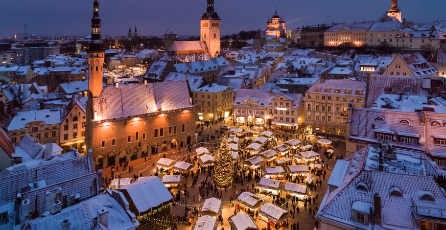 Veduta dall’alto del mercatino di Natale di Tallinn, tra bancarelle illuminate e tetti innevati.