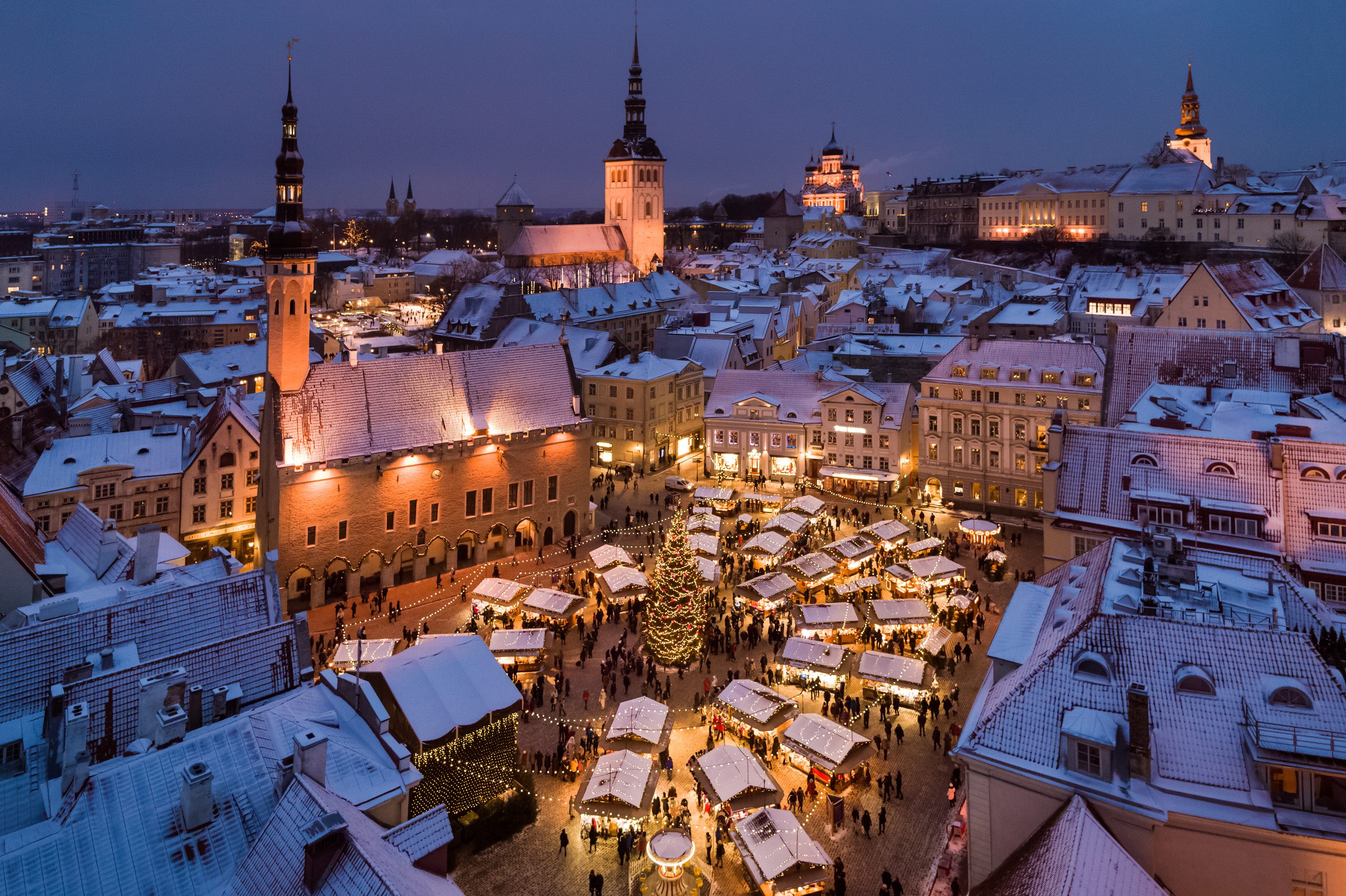 Veduta dall’alto del mercatino di Natale di Tallinn, tra bancarelle illuminate e tetti innevati.