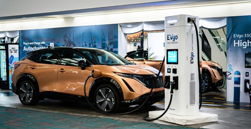 Auto elettrica arancione collegata a una colonnina di ricarica rapida