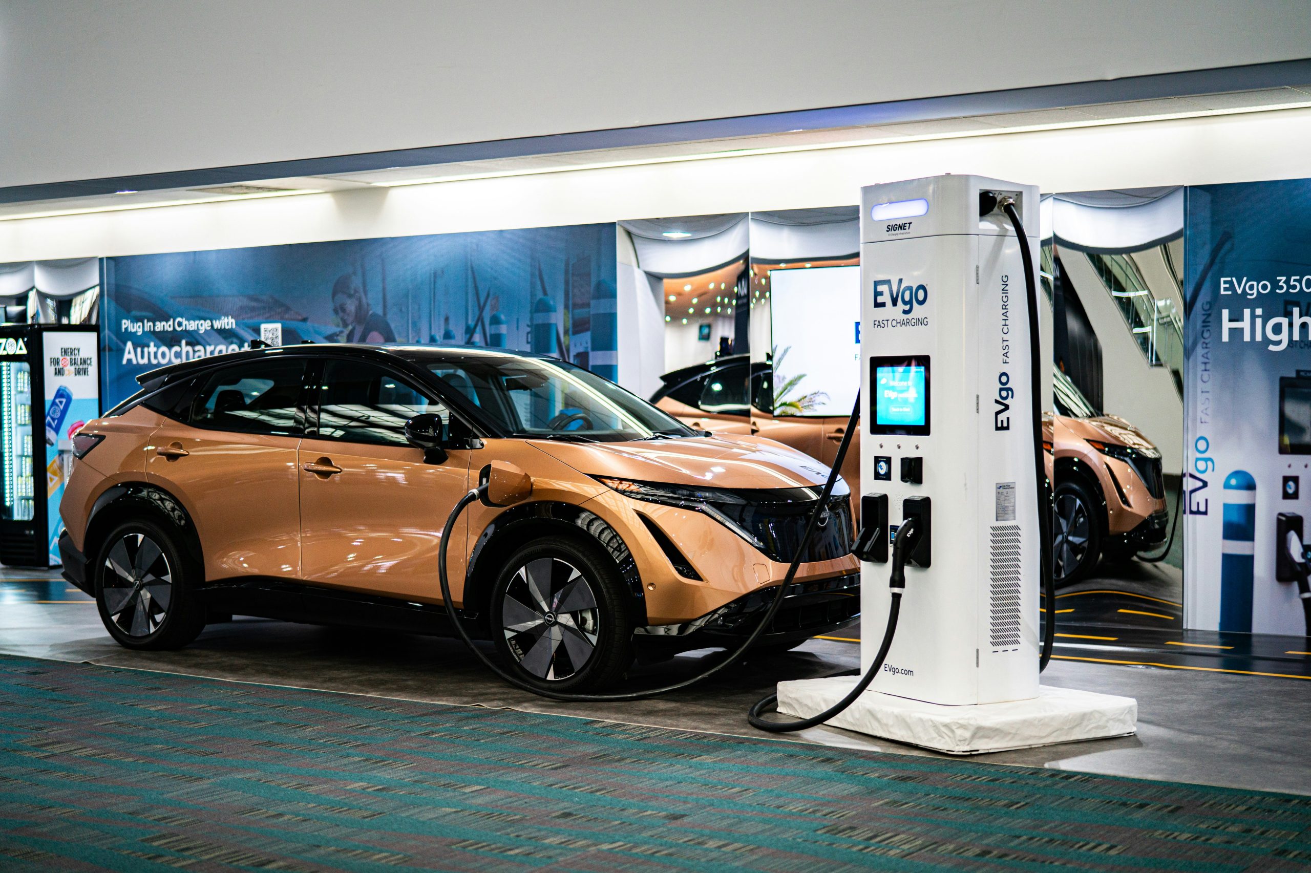Auto elettrica arancione collegata a una colonnina di ricarica rapida